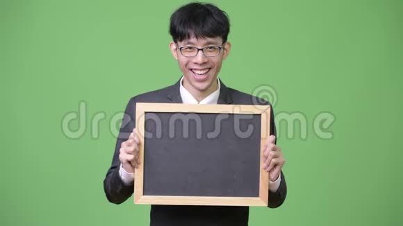 年轻快乐的亚洲商人微笑一边展示黑板镜头视频的预览图