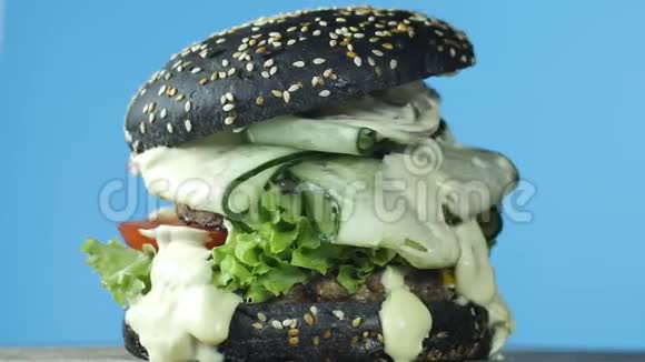 孤立的汉堡包在蓝色背景上旋转大汉堡肉饼和黑面包洋葱黄瓜融化视频的预览图