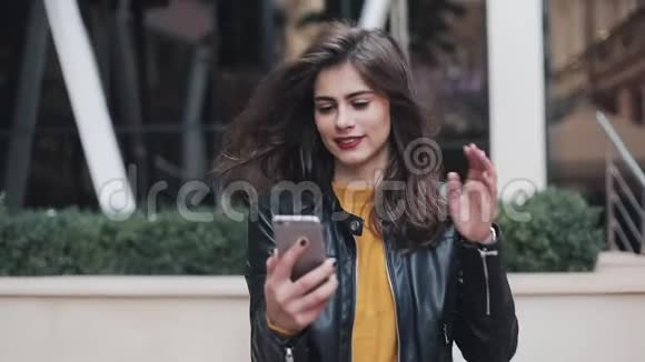 幸福的年轻女性在视频上讲话的肖像手机上的电话站在街道上的大楼附近视频的预览图