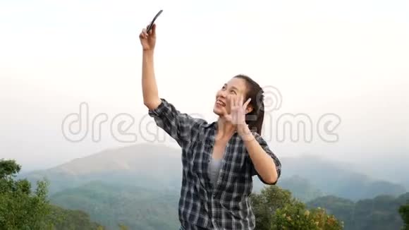4K镜头美丽的亚洲女性使用智能手机进行视频聊天户外与朋友分享旅游自然景观或现场直播视频的预览图