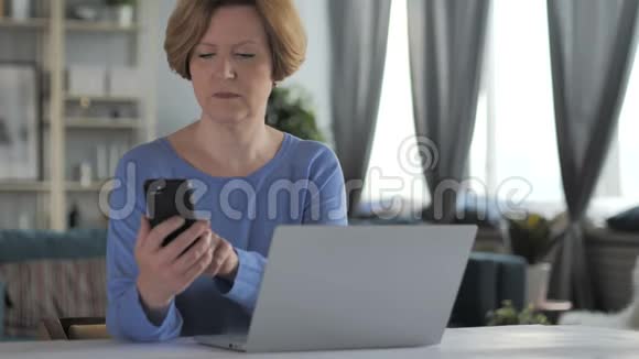 工作场所使用智能手机和笔记本电脑的老年妇女视频的预览图