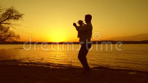 在日落时分爸爸和他的小女儿在一个美丽的湖上跳舞视频的预览图