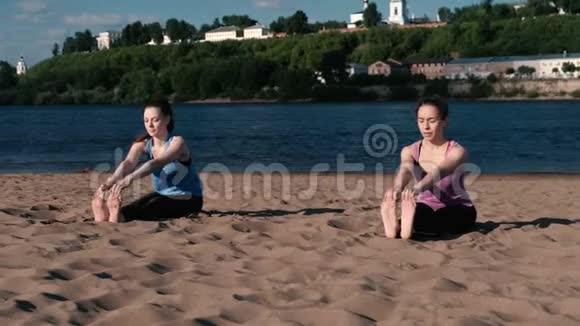 两个女人在城市河边的海滩上做瑜伽城市美景帕希莫塔纳萨纳瑟萨萨纳姿势视频的预览图