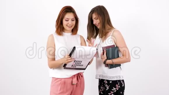 两个年轻的女人一个手里拿着剪贴板另一个拿着一些书视频的预览图