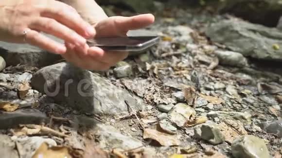 近距离徒步旅行女性手工制作图片蚂蚁智能手机在山河大巨石和绿色苔藓视频的预览图