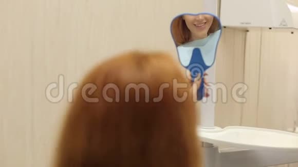 年轻快乐的女客户在牙科办公室看着镜子视频的预览图