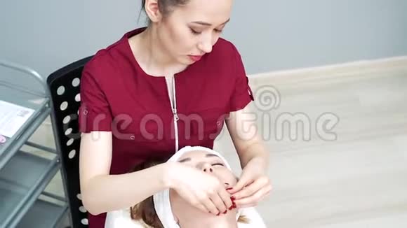 美容师在水疗沙龙为年轻女性做放松面部按摩视频的预览图
