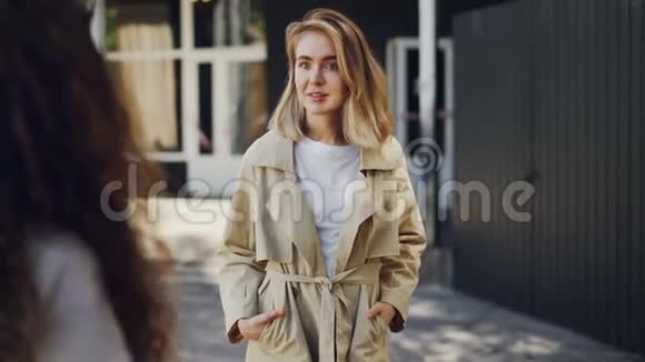 迷人的女孩正在和她的朋友交谈她站在城市的街道上手势分享新闻情感青年视频的预览图
