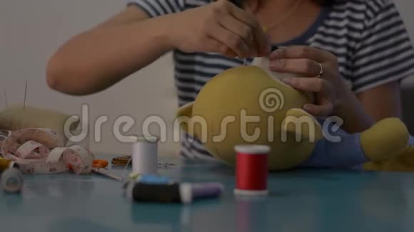 女人在家里的桌子上缝制和固定泰迪熊娃娃视频的预览图