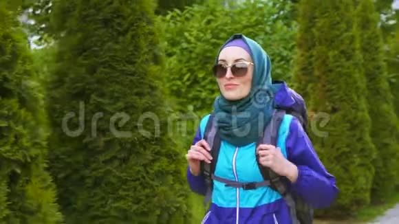 戴着眼镜背包的美丽的旅游女孩微笑着走视频的预览图
