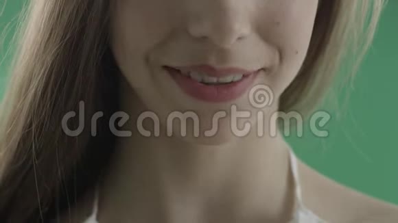 在绿色背景下微笑性感年轻女人的性感嘴唇视频的预览图