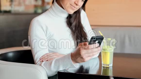 一个年轻女孩坐在咖啡店里看着电话视频的预览图