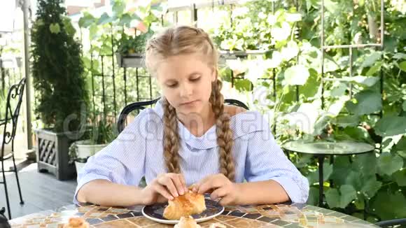 出去吃饭可爱的可爱女孩吃牛角面包并表现出认可的姿态拇指向上快乐的童年视频的预览图