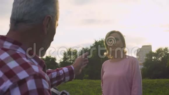 五十多岁的男人在日落时分在公园里为他美丽的妻子拍照爱好约会视频的预览图
