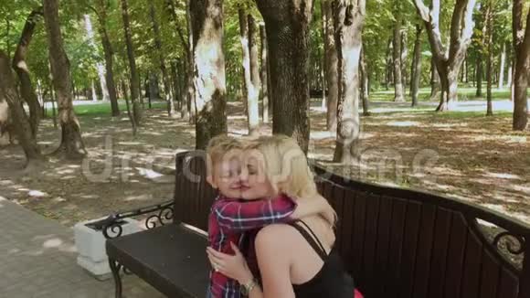 美丽的小男孩在公园里的长凳上给他心爱的母亲一束花视频的预览图