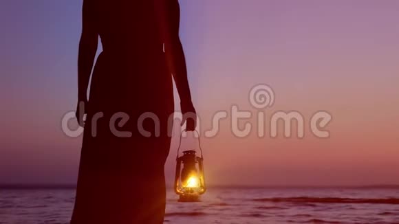 在夕阳下的天空背景下穿着盛装的孤独女子手持煤油灯视频的预览图