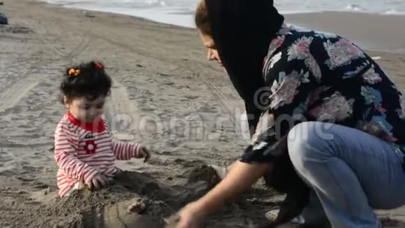 母亲和幼儿在沙滩上玩沙子视频的预览图