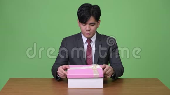 年轻的亚洲商人在打开礼品盒时显得很高兴和惊讶视频的预览图