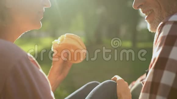 女性和男性退休者在野餐时吃汉堡浪漫约会特写视频的预览图