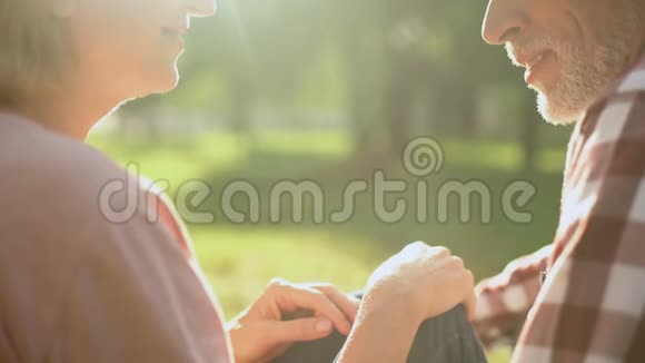微笑着的退休夫妇在公园里放松牵手谈论爱情视频的预览图