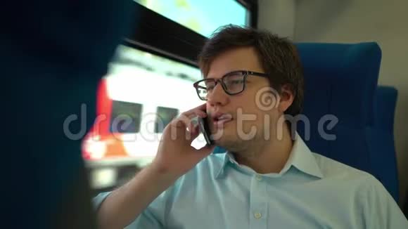 戴眼镜的中年男人坐火车打电话微笑视频的预览图