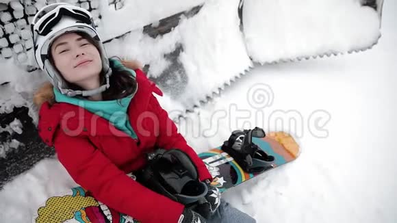 女孩正拿着一块滑雪板躺在雪地上视频的预览图