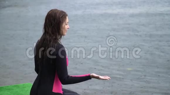 穿着湿衣服的漂亮女孩正坐在雨中的码头上视频的预览图