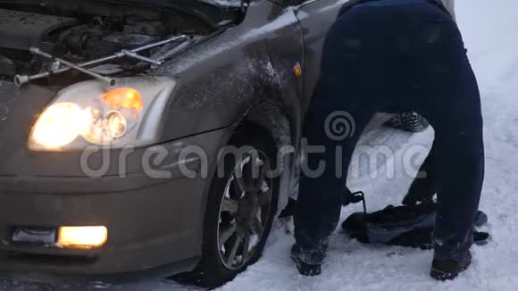 人举起汽车杰克汽车在一条下雪的路上抛锚了视频的预览图