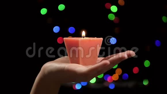 在闪烁的灯光背景下美丽的燃烧蜡烛在女性手中一个女人把蜡烛吹灭视频的预览图