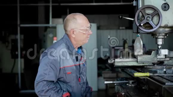 生产中的老人机器上的工人钻金属零件视频的预览图