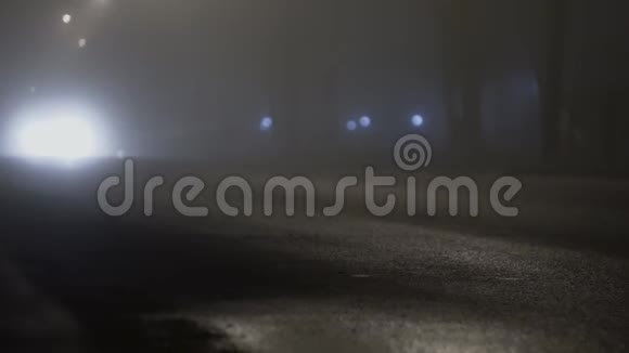 一辆开着前灯的汽车在夜间雾中行驶在道路上由于雾而能见度不佳视频的预览图