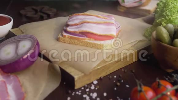 用切片的培根泡菜和蔬菜在木板上做三明治在光线下做视频的预览图