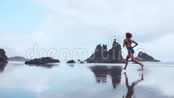 女人在冰冻岩浆背景下的加那利群岛黑色火山沙上奔跑健康的概念视频的预览图