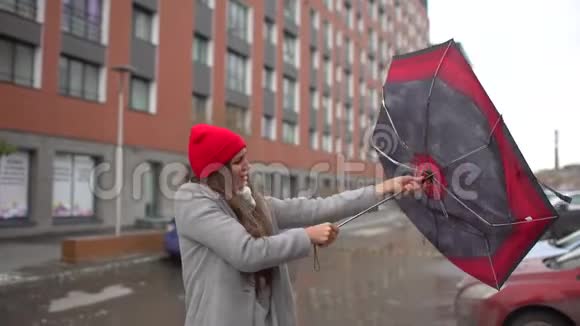 年轻的女性带着雨伞站在户外的女孩一阵风把伞拔出手来雨伞女孩视频的预览图