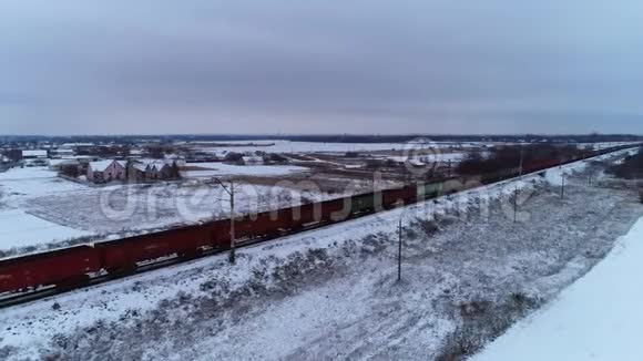 一列很长的火车经过一个覆盖着雪的小村庄空中射击视频的预览图