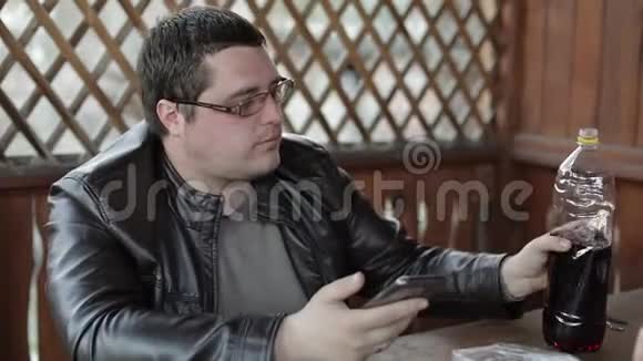 男人坐在桌边喝塑料瓶里的啤酒快乐视频的预览图