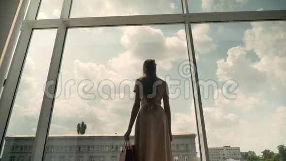 年轻漂亮女孩的剪影走进商场的橱窗手拿包包购物理念时尚理念底景视频的预览图