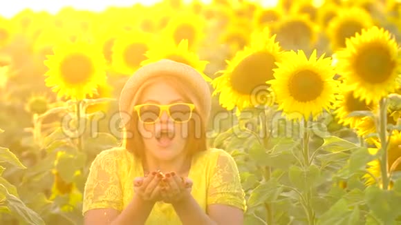 红色长发的美女站在黄色的向日葵田里吹着金色的闪光户外快乐的女人青少年视频的预览图