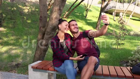 年轻情侣自拍坐在公园长椅上视频的预览图