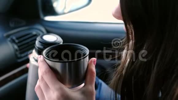 特写镜头一个面目全非的女人在冬天坐在车里的热水瓶里喝着一杯热茶视频的预览图