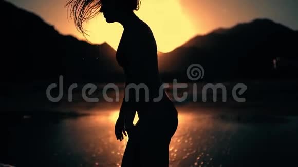 站在夕阳下的女人剪影摆动湿发视频的预览图
