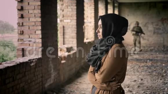 军人年轻的穆斯林妇女站在废弃的建筑里士兵带着恐惧和悲伤走向女人视频的预览图