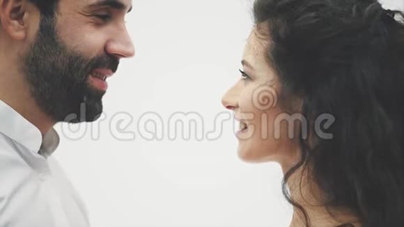 一个慈爱的丈夫和女人越来越接近亲吻对方快乐的年轻性感夫妇抚摸着他的鼻子微笑视频的预览图