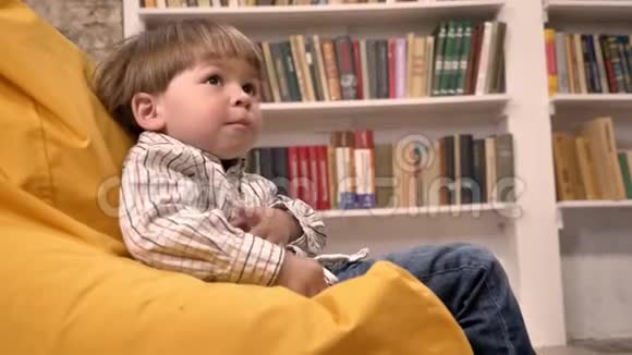 小男孩把球扔了开心地笑着书架上有书背景视频的预览图