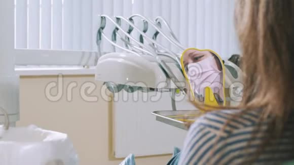 近看镜中一个年轻微笑的女孩手术结束后病人坐在牙科椅上视频的预览图