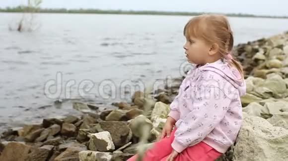 小女孩坐在河岸上视频的预览图