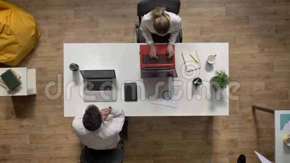 男人与女人讨论项目另一个男人在笔记本电脑上工作在电话上交谈顶级现代办公背景视频的预览图