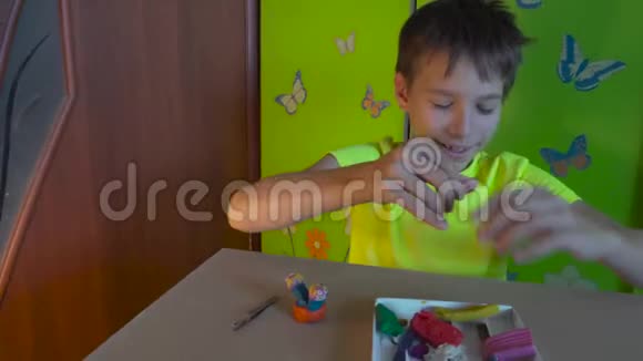 男孩坐在书桌前用彩色塑料雕刻图形发展良好的运动技能视频的预览图