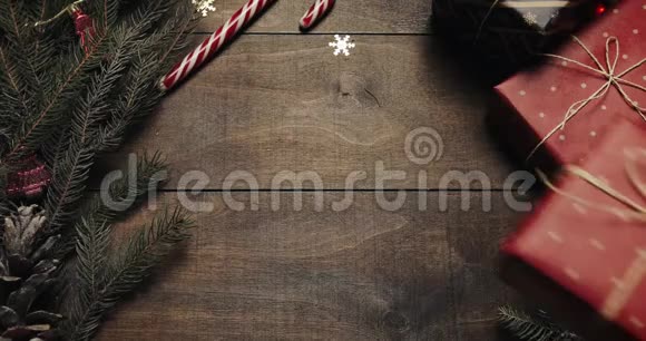 圣诞老人的手把新年礼物放在带有新年装饰和圣诞树的木制背景上视频的预览图