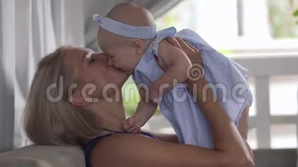 年轻的母亲亲吻她穿着蓝色衣服的小女儿视频的预览图